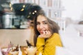 Portrait charming young woman with friendly smile, long brunette hair smiling in the window of cafe in winter time. True Royalty Free Stock Photo