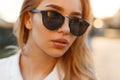 Portrait of a charming young woman with lips in black stylish sunglasses on sunset background. Attractive girl. Close-up. Royalty Free Stock Photo