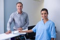 Portrait of cheeful doctor and man standing at desk