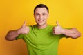 Portrait of cheeful handsome man raise thumb up symbol on yellow background