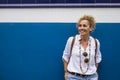 Portrait of cheerful adult blonde woman and blue and white wall in background Royalty Free Stock Photo