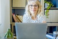 Portrait of cheerful adult woman sitting at the desk in modern office home workplace. Businesswoman or employess freelance people Royalty Free Stock Photo