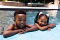 Portrait of cheerful african american siblings laughing while relaxing at poolside in resort Royalty Free Stock Photo