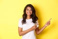 Portrait of cheerful african-american teenage girl, smiling happy and pointing fingers right at information banner Royalty Free Stock Photo