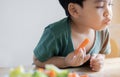 Portrait of cheerful Asian little boy eating salad and carrot with joy, he is looking aside with curiosity and smiling