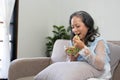 Portrait, Cheerful Asian 60s aged woman having breakfast in her living room, eating healthy salad vegetables mix bowl. Royalty Free Stock Photo