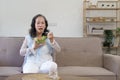 Portrait, Cheerful Asian 60s aged woman having breakfast in her living room, eating healthy salad vegetables mix bowl. Royalty Free Stock Photo