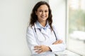 Portrait of cheerful young european woman doctor posing by window Royalty Free Stock Photo