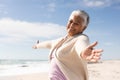 Portrait of cheerful biracial senior woman with arms outstretched enjoying retirement at sunny beach Royalty Free Stock Photo