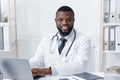 Portrait of cheerful black doctor at his workplace