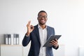 Portrait of cheerful black male psychologist showing okay gesture, recommending professional help at clinic