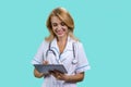 Portrait of cheerful blonde mature medical doctor woman using tablet device. Royalty Free Stock Photo