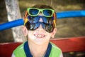 Portrait of a cheerful boy child in several sunglasses outdoors