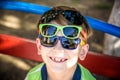 Portrait of a cheerful boy child in several sunglasses outdoors