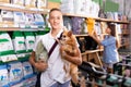 Portrait of cheerful boy with dog during selecting dry food in petshop, woman on background