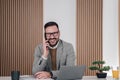 Portrait of cheerful businessman talking on phone while using laptop at office Royalty Free Stock Photo