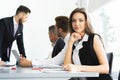 Portrait of a cheerful businesswoman sitting at the table in office and looking at camera. Royalty Free Stock Photo