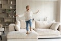 Portrait of cheerful carefree small girl jumping on sofa.