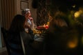 Portrait of cheerful Caucasian family celebrating Christmas, chatting at dinner holiday table in dark living room with Royalty Free Stock Photo