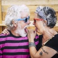 Portrait of cheerful caucasian senior crazy couple with wood background - alternative and young old people in funny expression -