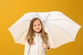 Portrait of a cheerful child in a beige jacket on a yellow background. Little girl blonde stands under the umbrella. Autumn Royalty Free Stock Photo