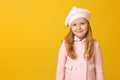 Portrait of a cheerful child in a pink coat and beret on a yellow background. Little girl blonde looks into the camera. Autumn Royalty Free Stock Photo