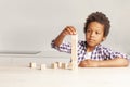 Portrait of cheerful child small boy playing and building a tower of wooden blocks in white interior Royalty Free Stock Photo