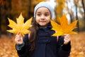 Portrait of cheerful children holding two dry yellow autumn leaves in hands. Royalty Free Stock Photo