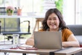 Portrait of cheerful chubby asian businesswoman smiling and sitting on a floor looking at a camera using a computer laptop in a Royalty Free Stock Photo