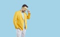 Portrait of cheerful cool and stylish millennial man in colorful outfit on light blue background.