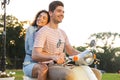 Portrait of man and woman riding on scooter together through city street Royalty Free Stock Photo