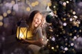 Portrait of a cheerful cute girl near a Christmas tree with a lantern. New Year holidays
