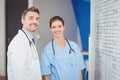 Portrait of cheerful doctors standing by chart on wall