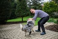 Portrait of cheerful down syndrome adult man playing with dog outdoors in backyard. Royalty Free Stock Photo