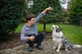 Portrait of cheerful down syndrome adult man training dog outdoors in backyard. Royalty Free Stock Photo