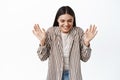 Portrait of cheerful dreamy woman close eyes and laugh, raising hands up happy, smiling with delight, standing against Royalty Free Stock Photo