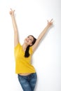 Portrait of cheerful European woman with hands raised pointing up