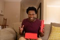 Portrait of cheerful excited african american man opening valentine\'s present box sitting at home Royalty Free Stock Photo