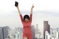 Portrait of cheerful excited pretty young female standing with skyscraper city view. Attractive woman in red dress holding digital Royalty Free Stock Photo