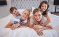 Portrait of a cheerful family lying together on bed. Little boy and girl lying on their parents laughing and having fun Royalty Free Stock Photo