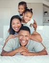 Portrait of a cheerful family lying on top of their father on a bed. Two children and wife lying on dads back laughing Royalty Free Stock Photo