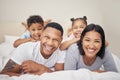 Portrait of a cheerful family with two children lying together on bed. Little boy and girl lying on their parents Royalty Free Stock Photo