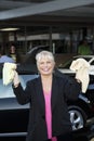 Portrait of cheerful female owner showing washcloth in car wash