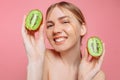 Attractive girl holding kiwi slices, on a pink background. Natural beauty Royalty Free Stock Photo