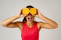 Portrait of cheerful funny and attractive woman holding sliced orange over her eyes Royalty Free Stock Photo