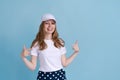 Portrait cheerful girl straight fingers herself on in white cap on blue Royalty Free Stock Photo