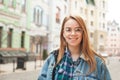 Portrait of a cheerful girl wearing casual clothing, standing in headphones, background of the landscape of the old town,looking Royalty Free Stock Photo