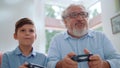 Portrait of cheerful grandson and grandfather playing video game in living room Royalty Free Stock Photo