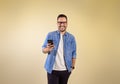 Portrait of cheerful handsome entrepreneur with hand in pocket messaging online over smart phone. Happy young man dressed in blue Royalty Free Stock Photo