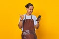 Portrait of cheerful handsome man looking at mobile phone with finger showing sales discount over yellow background Royalty Free Stock Photo